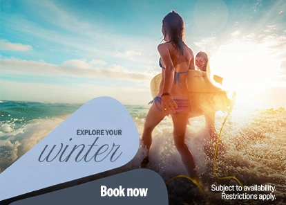 Winter 2025 travel promotion featuring women with a surfboard on the beach.